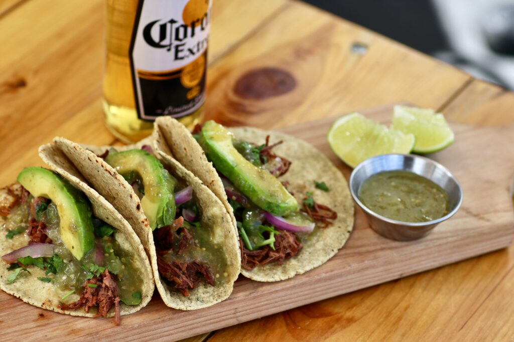 A colorful arrangement of authentic tacos from Carintias, featuring several soft corn tortillas piled high with seasoned meats, fresh cilantro, and diced onions.