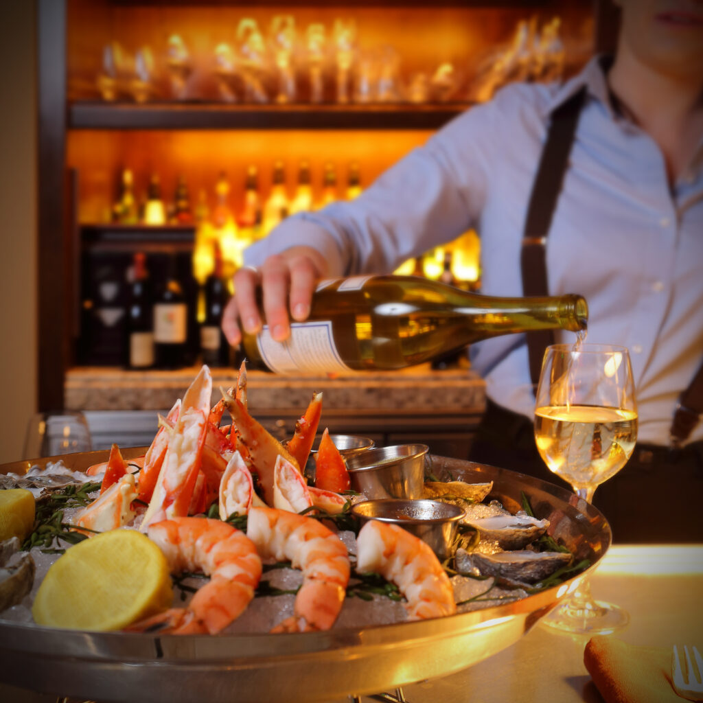 Chilled seafood tower with king crab legs, jumbo shrimp, and oysters served with white wine at a luxury Park City restaurant.