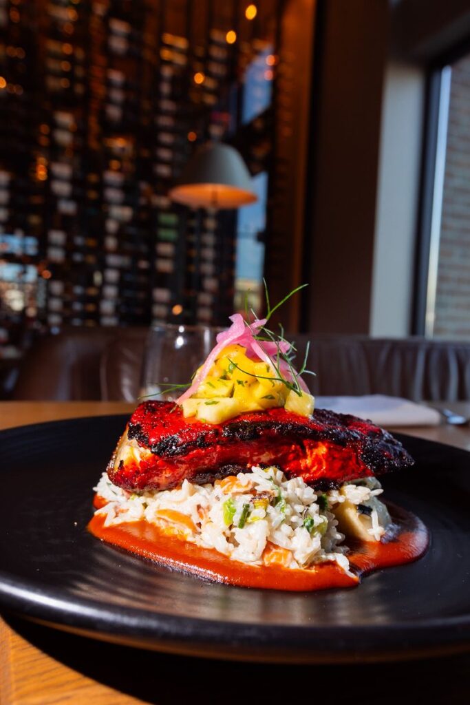 A beautifully plated gourmet dish featuring seared pork belly served over a vibrant pea purée with fresh greens and mustard seed garnish at a luxury Park City restaurant.
