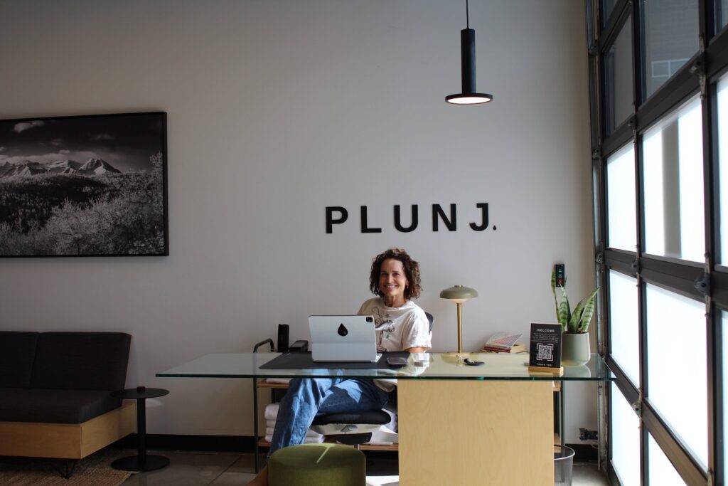 Owner Kimberly Ence at the Plunj Park City welcome desk, providing information on recovery sessions for those looking for the best dining in Park City and Kimball Junction restaurants.