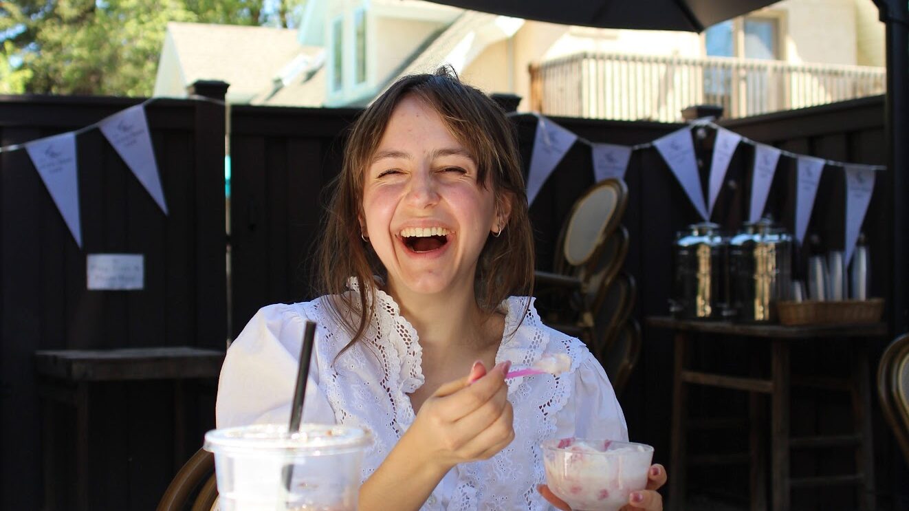 A guest enjoying artisan sandwiches, dessert, and iced coffee on the sunny outdoor patio at one of the best Midway restaurants.